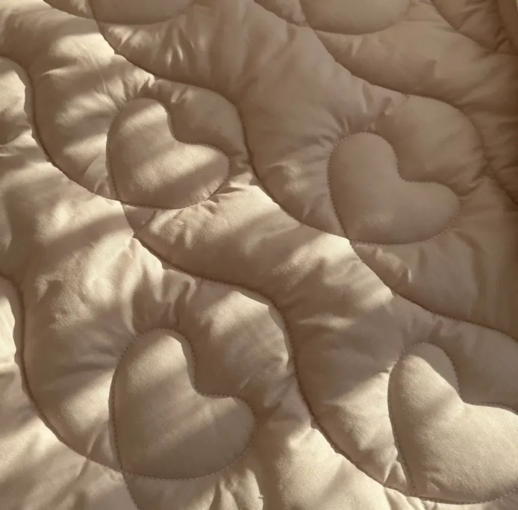 Close-up of the powder pink comforter quilted with hearts and waves